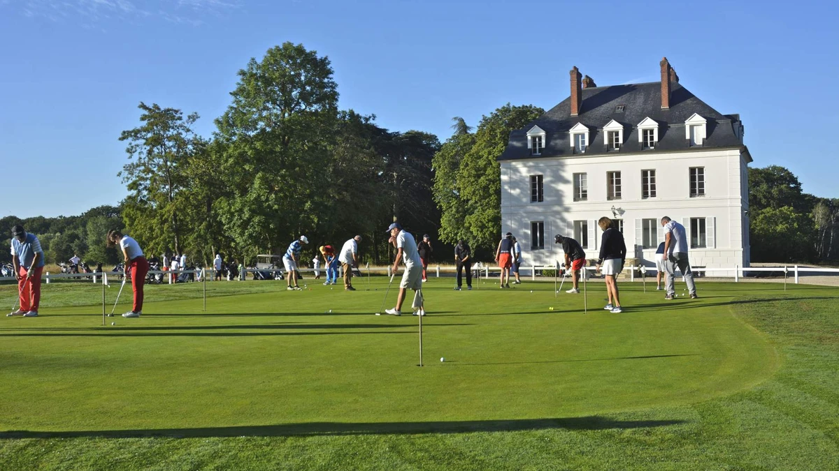 Putting-green avec joueurs devant le domaine ; zone d’entraînement exacte, pas vue générale du 18 trous. — Domaine et Golf du Roncemay