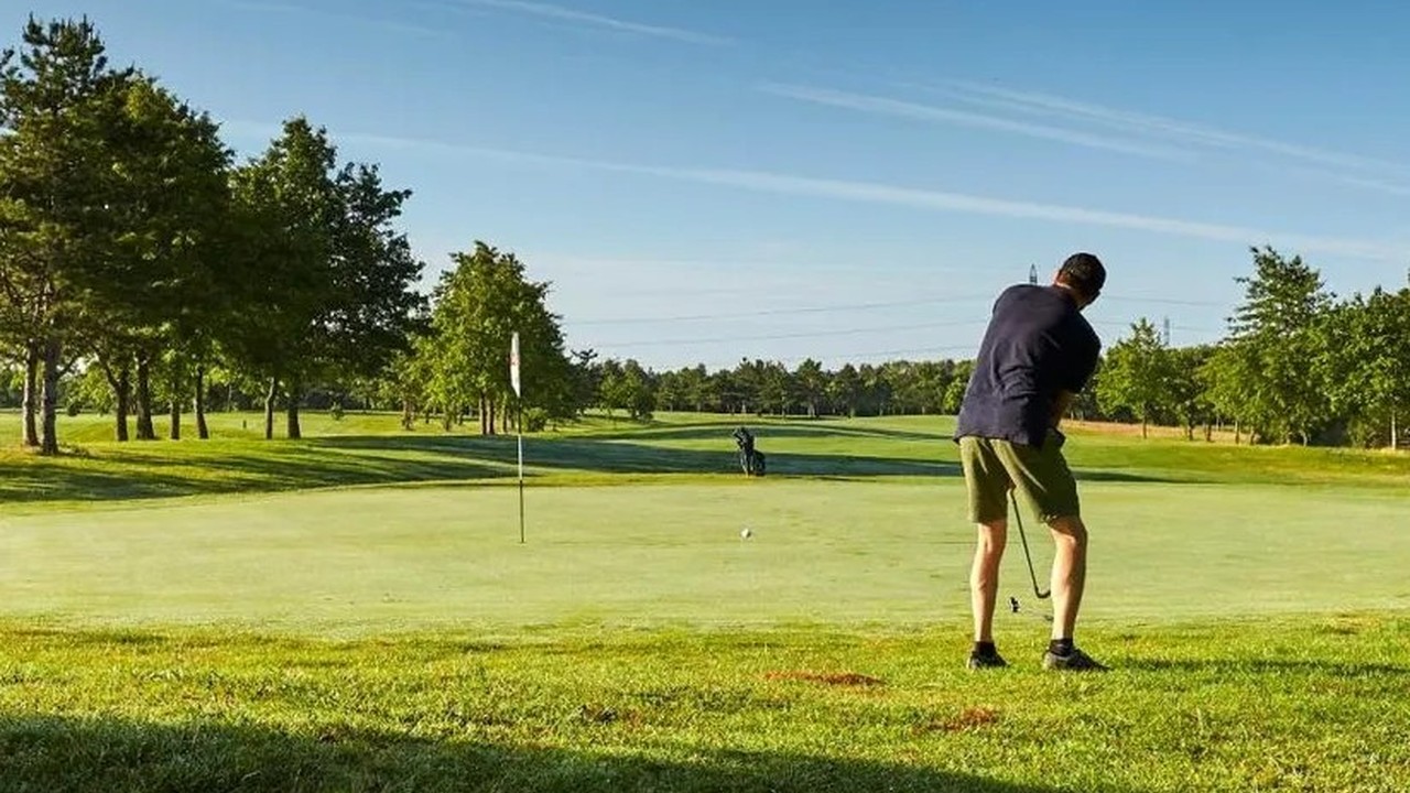 Golfeur jouant une approche vers un green bordé d’arbres au Golf Bluegreen Bordeaux-Lac.