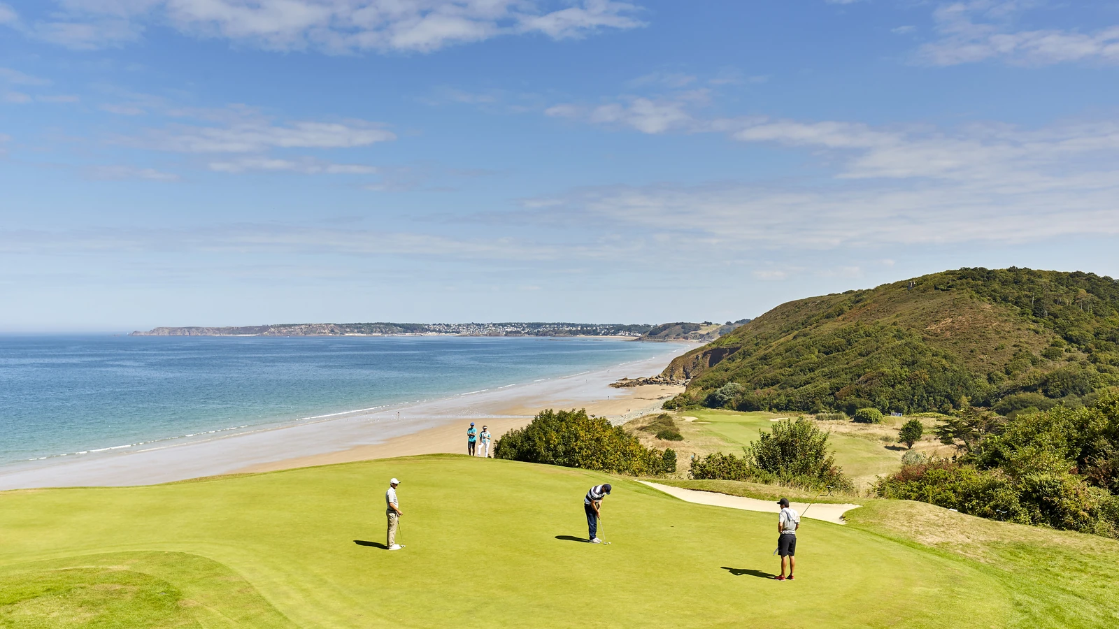 Golfeurs sur un green dominant la plage et les falaises au Golf Bluegreen Pléneuf-Val-André.