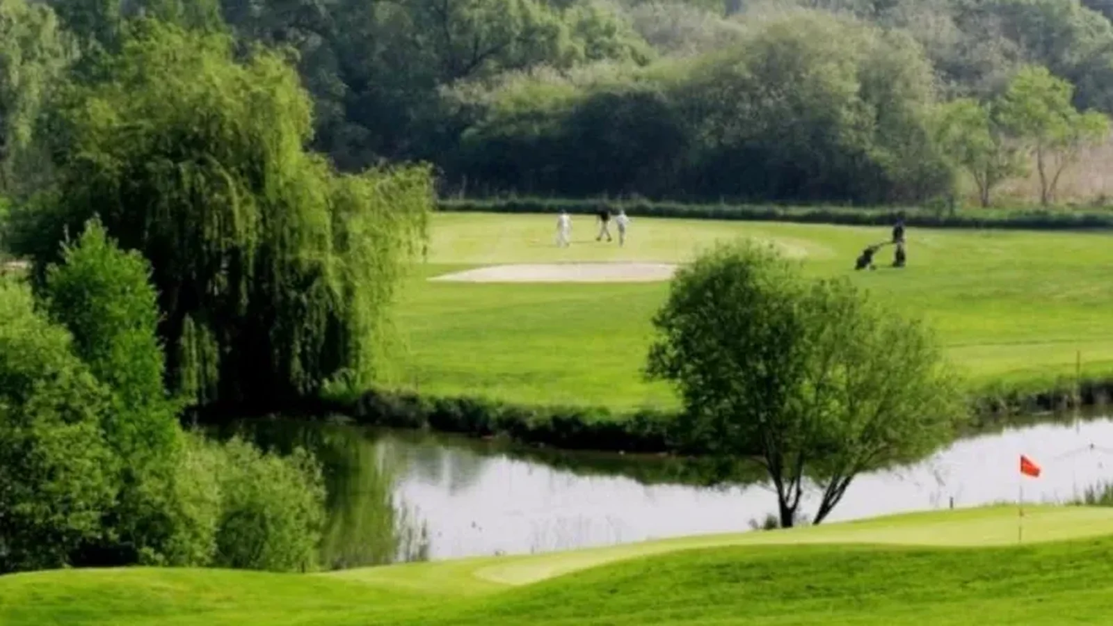 Green et plan d’eau du Golf Club d’Ableiges dans un paysage arboré.