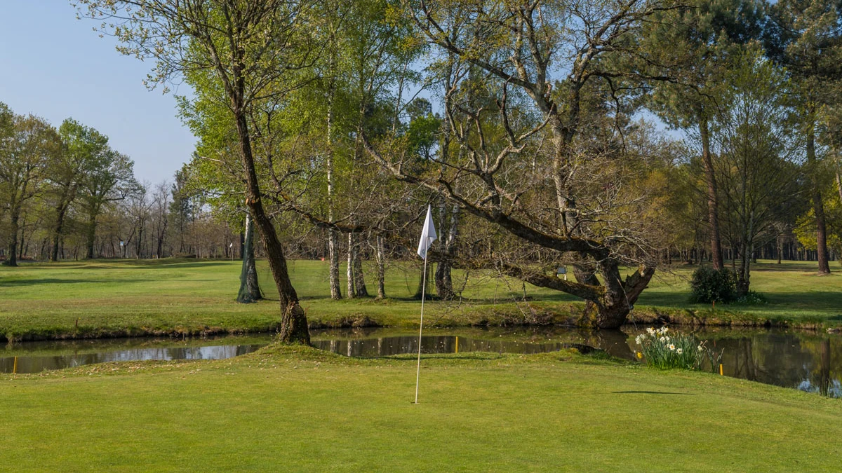 Green avec drapeau blanc et obstacle d’eau au Golf Club de Montendre.