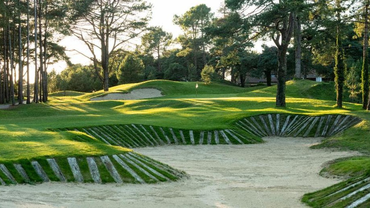 Grand bunker au premier plan et green entouré de pins au Golf d’Hardelot.