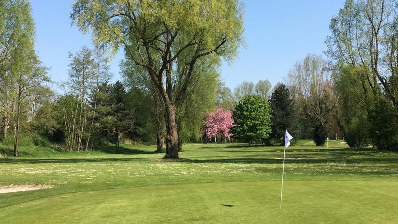 Green avec drapeau blanc, grands arbres et arbre en fleurs au Golf de Béthune.