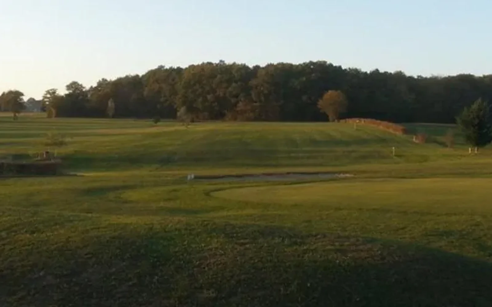Vue du parcours en lumière rasante, bordé d’arbres. — Golf de Bourbon-Lancy