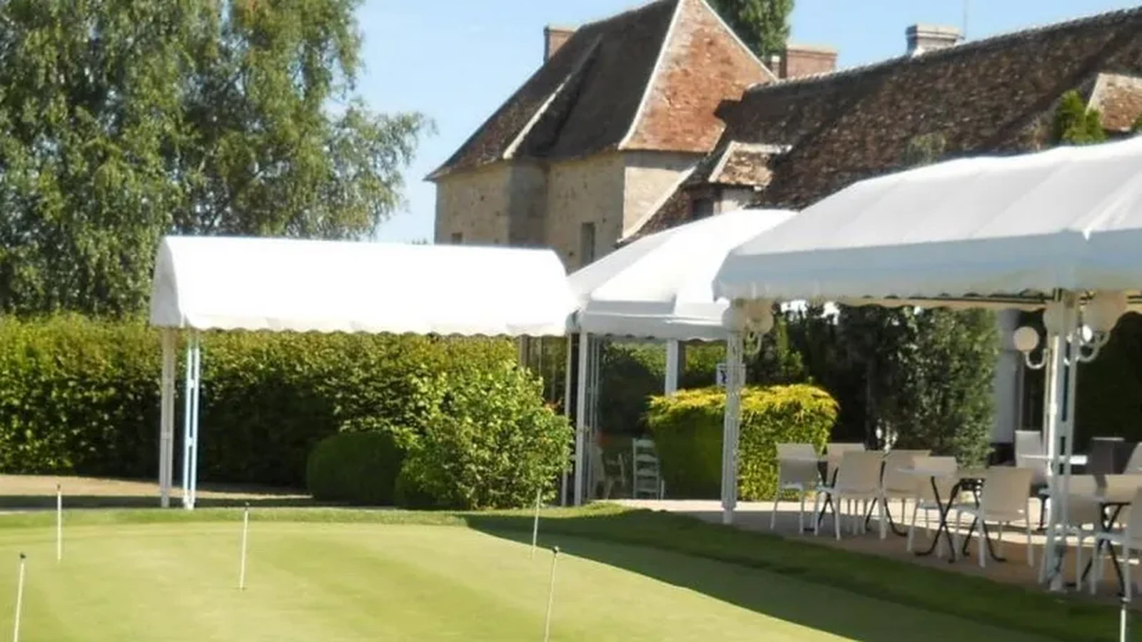 Zone d’entraînement et putting green devant les bâtiments du Golf de la Forteresse.