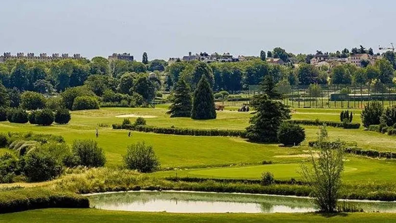 Vue du Golf de Paris avec fairway, arbres et obstacle d’eau.