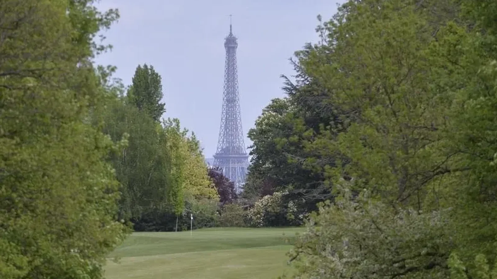Fairway arboré du Golf de Saint-Cloud avec la tour Eiffel à l’arrière-plan.