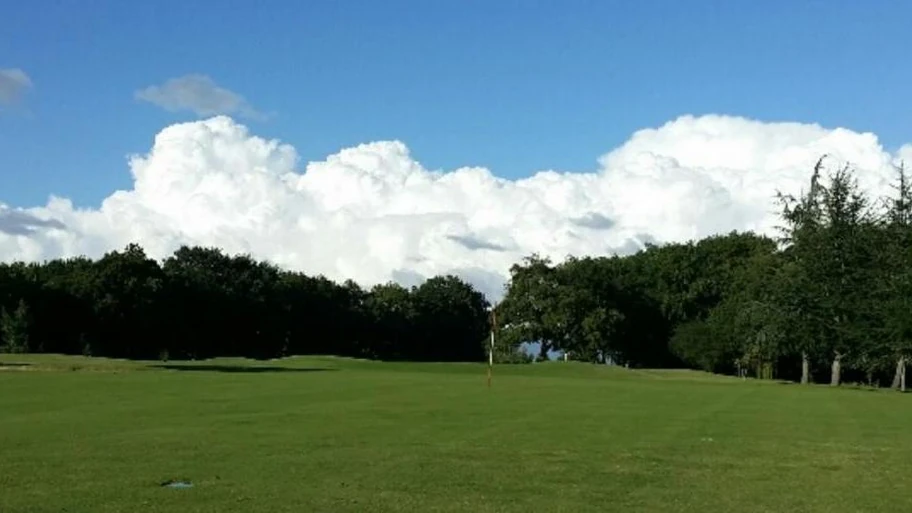 Green avec drapeau bordé d’arbres au Golf de Saintes.