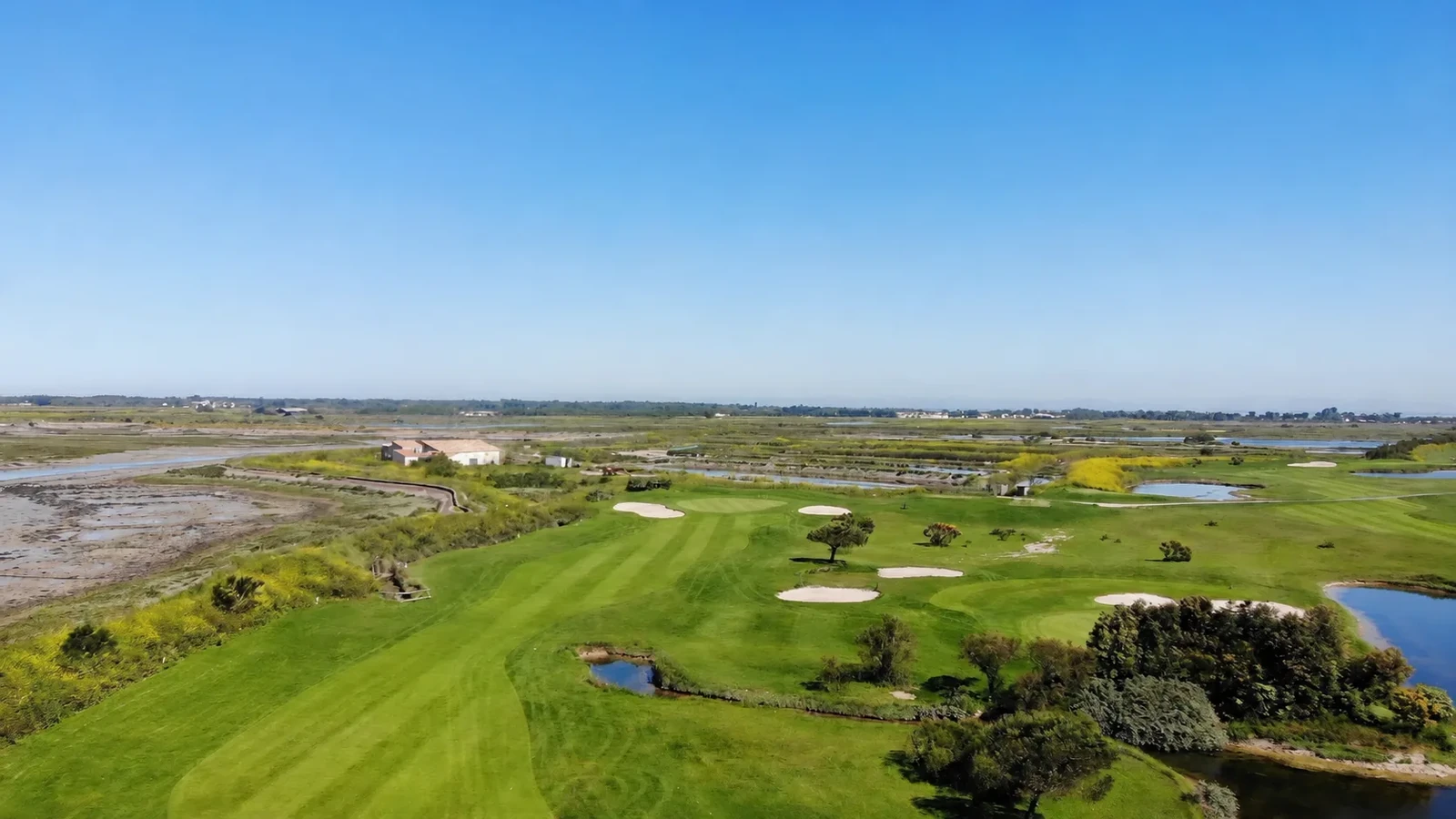 Vue aérienne des fairways, greens et bunkers du Golf de Trousse-Chemise entre océan et marais.