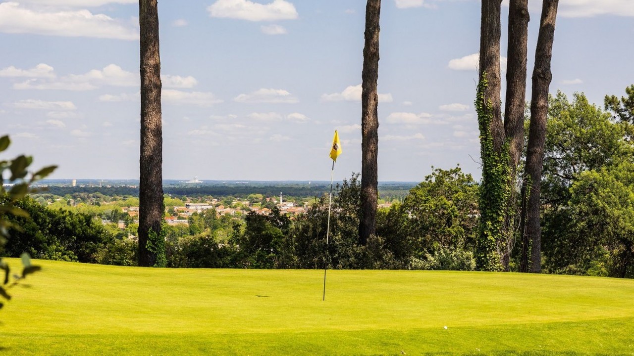 Green avec drapeau jaune entre les pins au Golf International d’Arcachon.