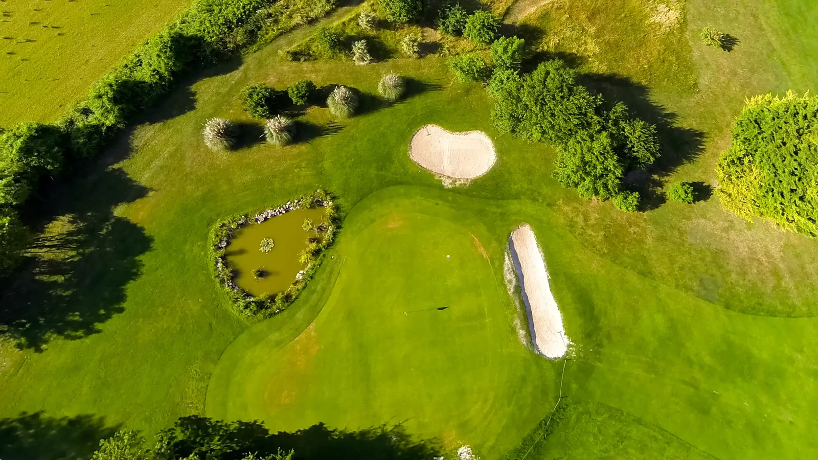 Vue aérienne d’un green, de deux bunkers et d’un petit obstacle d’eau au Golf La Rochelle Sud.