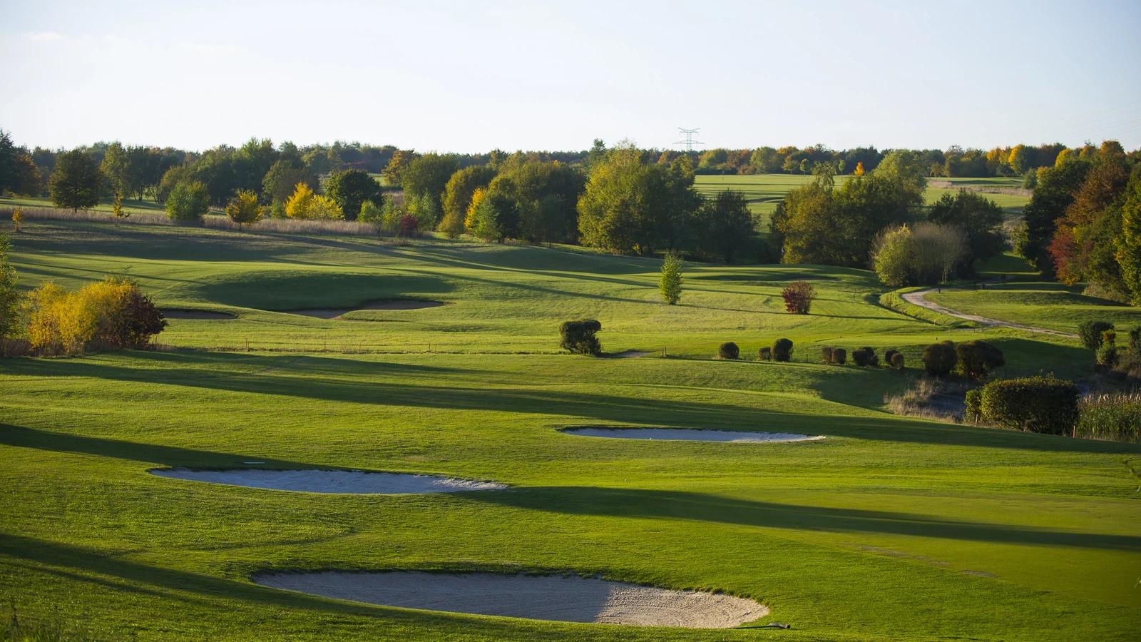 Fairways et obstacles d’eau du Golf municipal d’Évreux dans un paysage arboré.