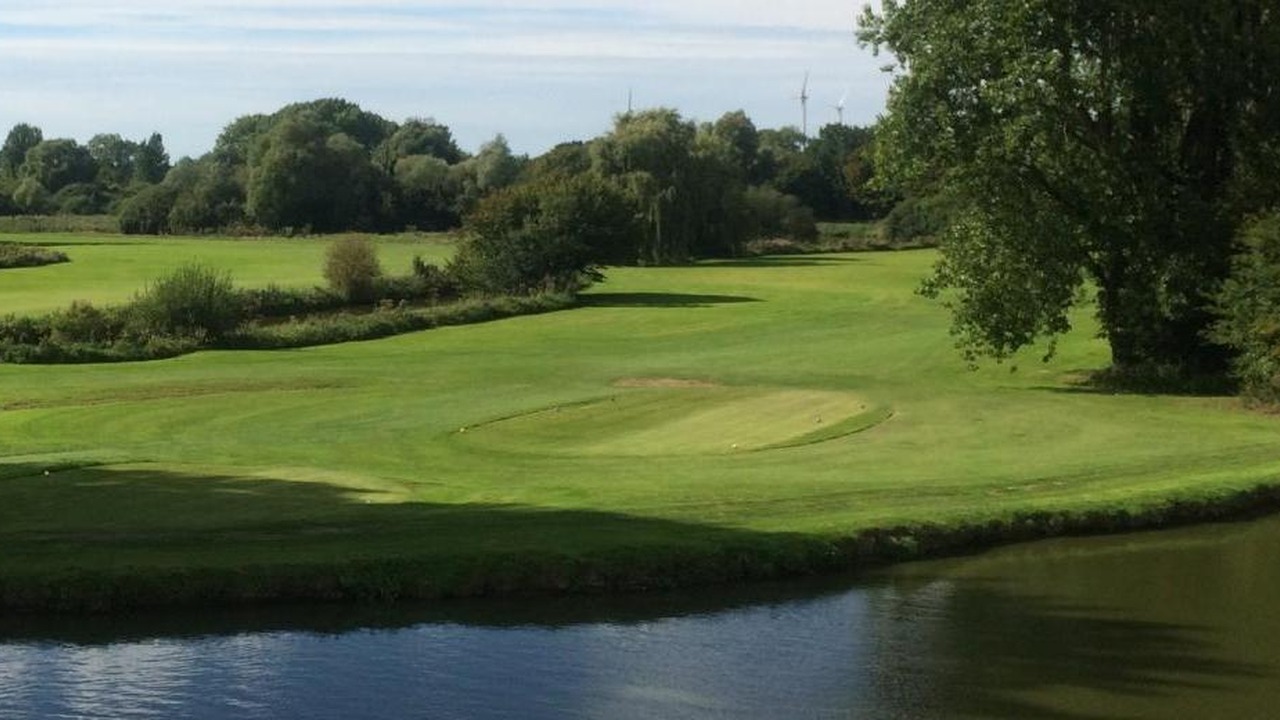 Green et fairway bordés d’arbres, derrière un plan d’eau, au Nampont Saint-Martin Golf Club.