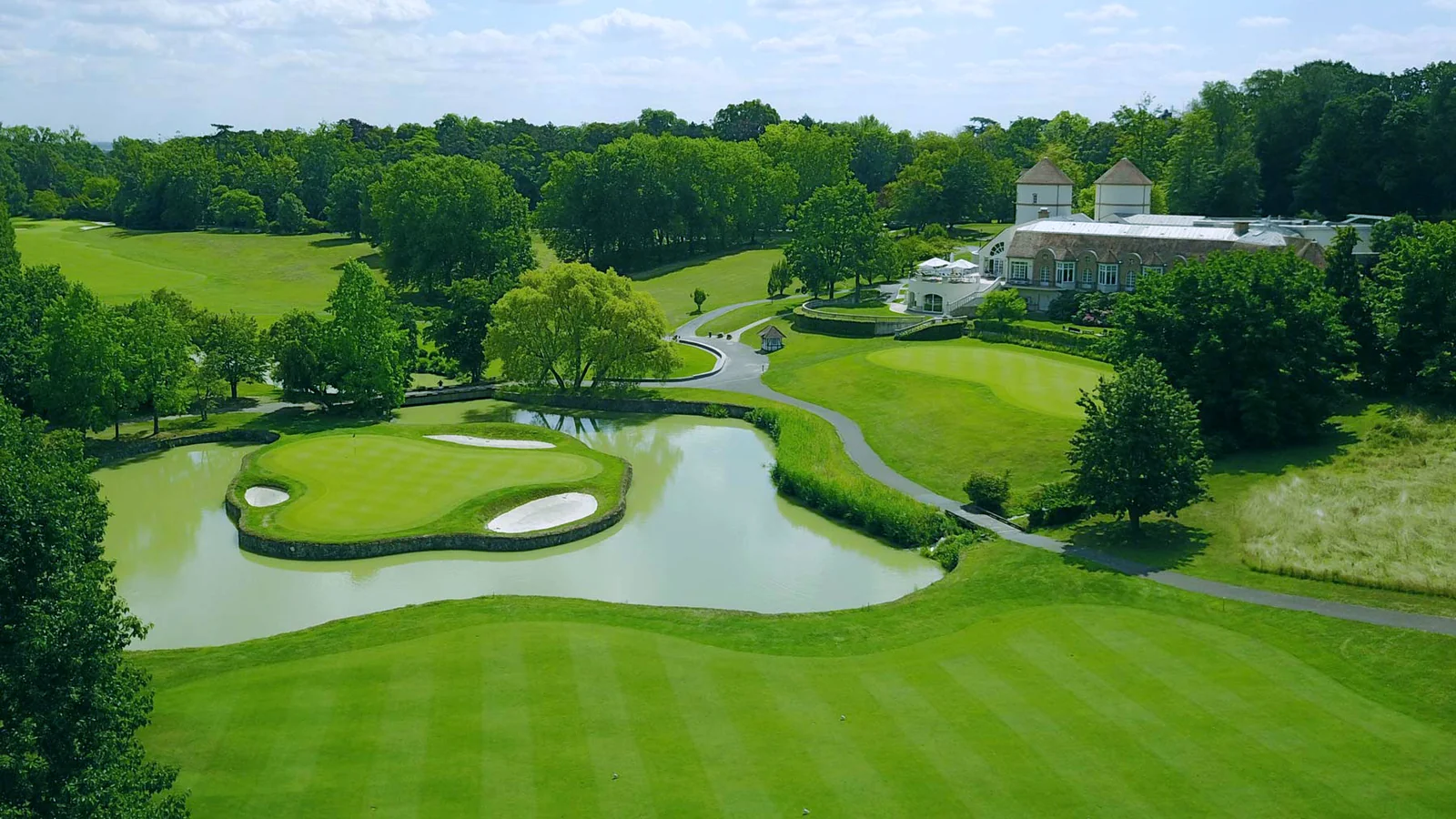 Vue aérienne du Paris International Golf Club avec fairways, greens, plans d’eau et club-house.