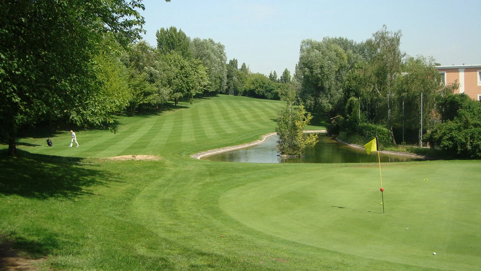 Green et fairway arboré d’UGOLF Rosny-sous-Bois, avec un obstacle d’eau.