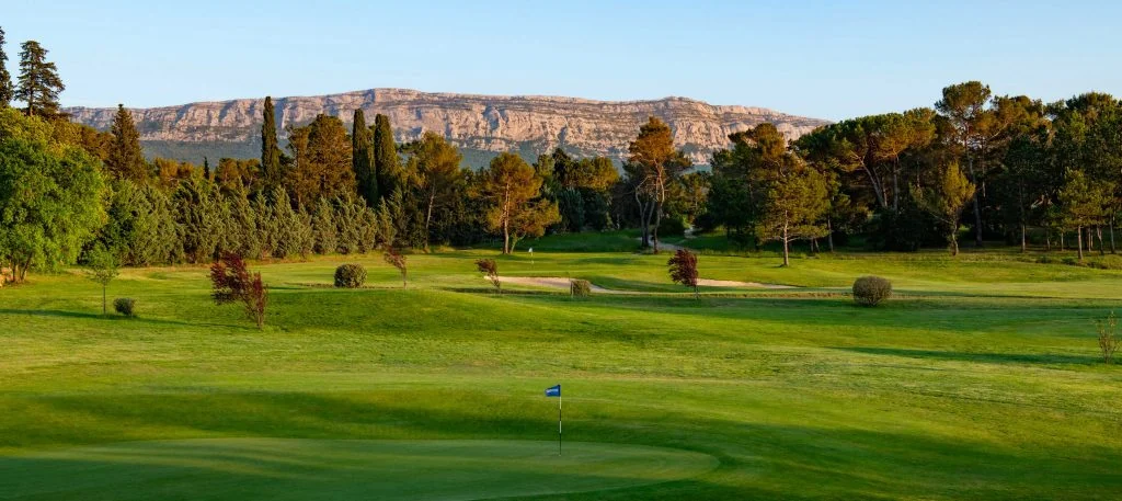 Green et fairways du Golf Sainte Baume devant la barre rocheuse du massif de la Sainte-Baume.
