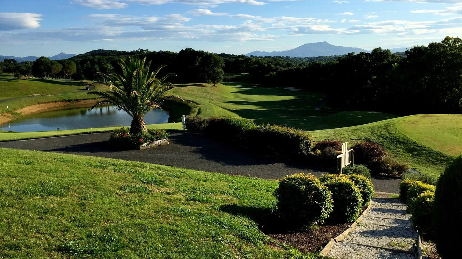 Vue du parcours du Makila Golf Club, de son plan d’eau et des montagnes en arrière-plan.