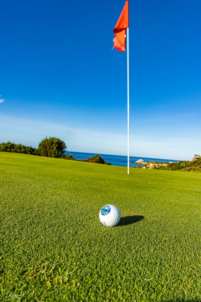 Balle et drapeau sur un green face à la mer — Golf de Spérone