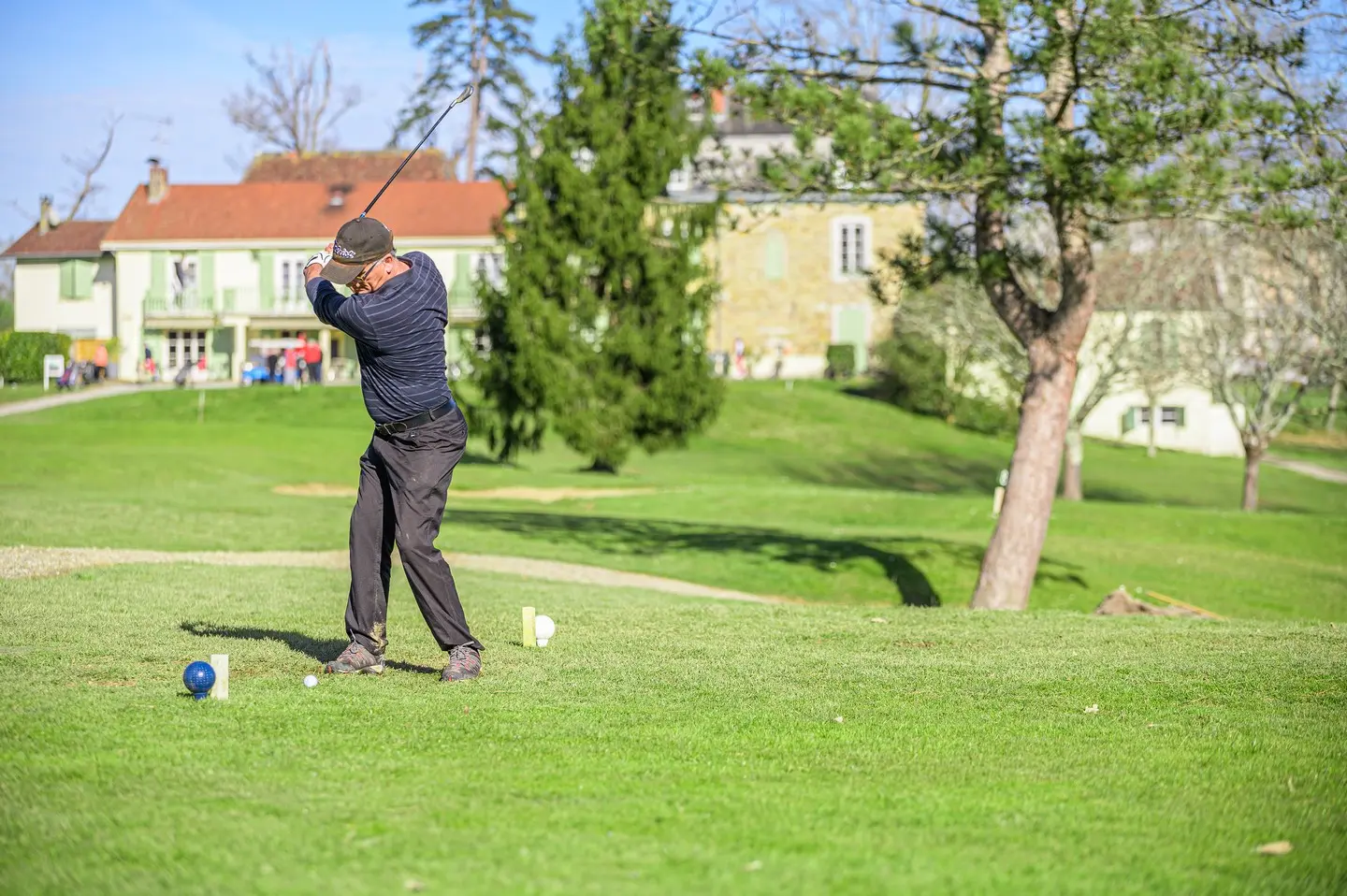 Golfeur au départ devant les bâtiments du Golf de Salies-de-Béarn.
