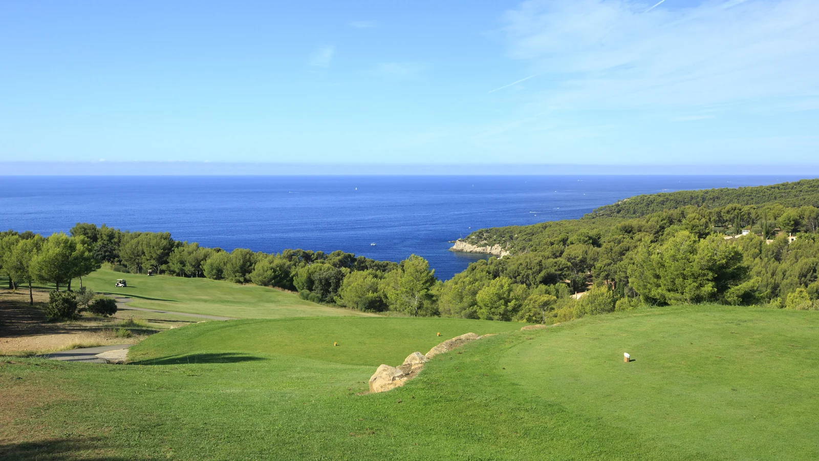 Départ et fairway de Frégate Provence Golf Club dominant la Méditerranée et une côte boisée.