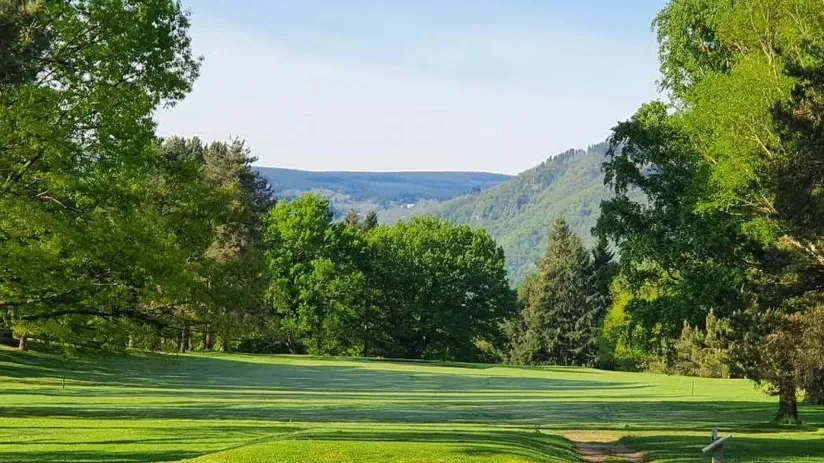 Fairway bordé d'arbres, avec les collines en arrière-plan