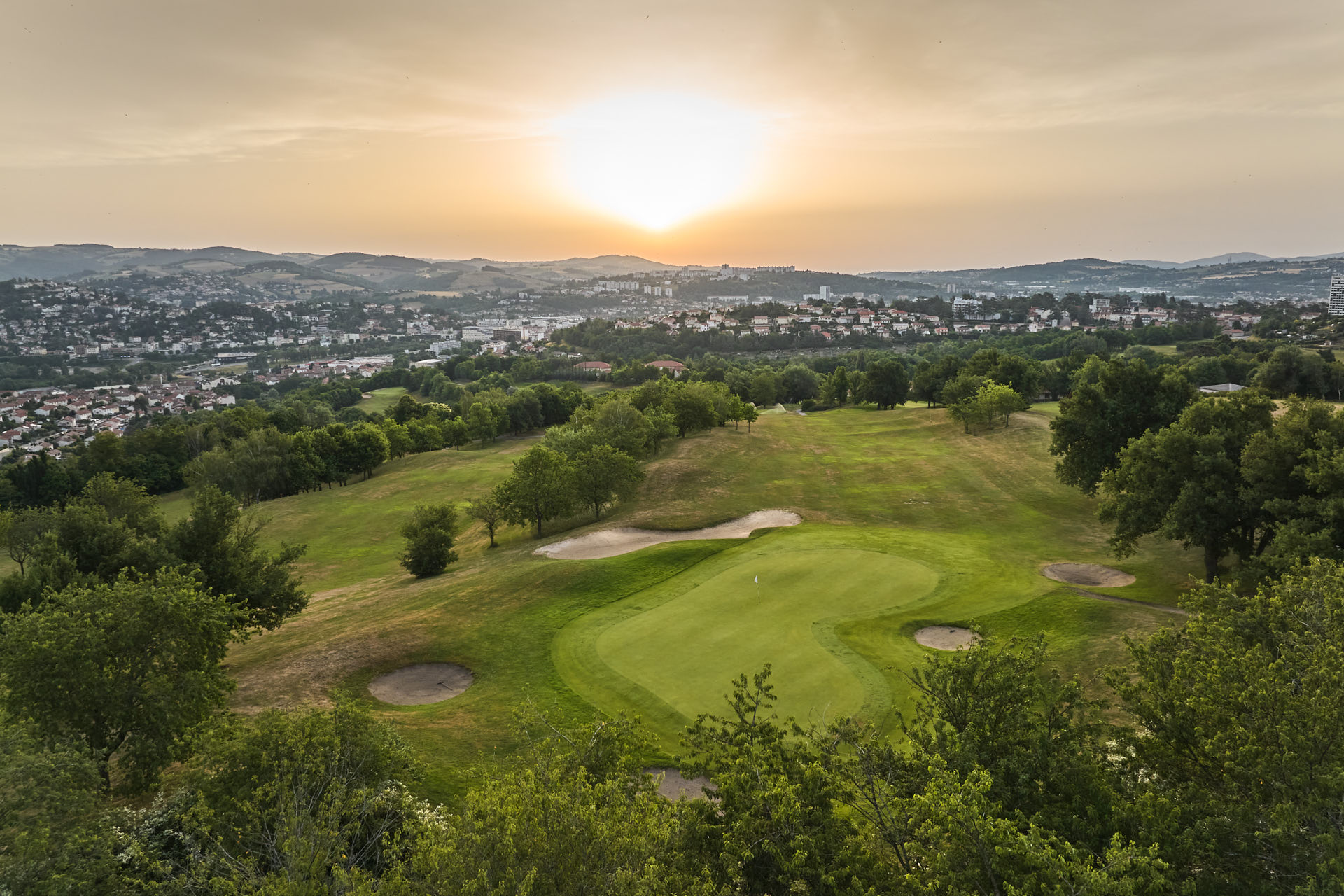 Vue aérienne du golf et de Saint-Étienne au soleil couchant.
