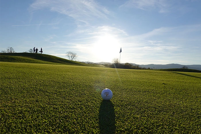 Drapeau et green au soleil bas au Golf du Domaine de Champlong.
