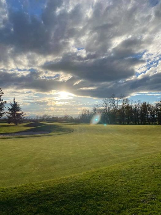 Vue du parcours du Golf Club du Forez sous un ciel nuageux.