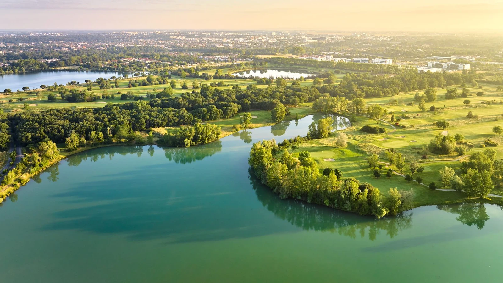 Vue aérienne du golf de La Ramée, avec plans d’eau, fairways et greens.